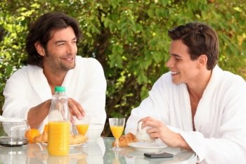 Two male housemates having breakfast outdoors