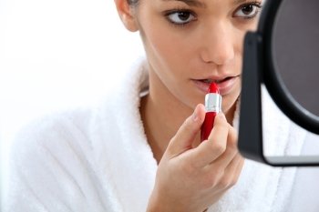 Woman applying lipstick in front of mirror