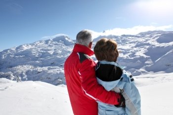 Middle-aged couple stood on secluded snowy mountain
