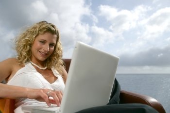 Blonde woman with a computer in front of the sea
