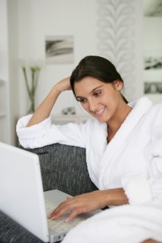 Brunette in bathing robe using laptop computer