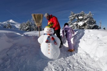 Father and daughter playing with snowman
