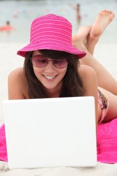 Brunette teenager at the beach with laptop computer