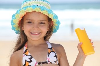 little girl on the beach with a sun cream