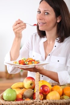 Health conscious brunette eating fruit salad