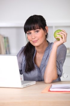 Woman with an apple sitting at her laptop