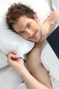 Young man smiling in bed