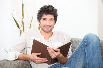 a man reading a book on couch