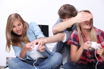 Three teenagers sat playing video games
