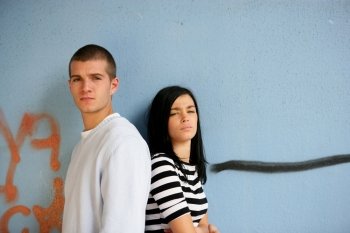 Two trendy teenagers stood against gratified wall