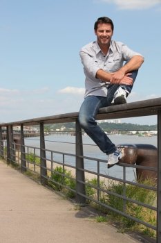 Man sitting on riverside railing