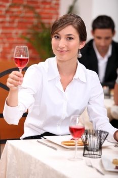 Young woman in a restaurant raising a glass of rose wine