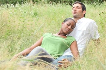 Mixed-race couple relaxing in a field