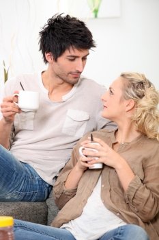 Man and woman drinking coffee on a couch