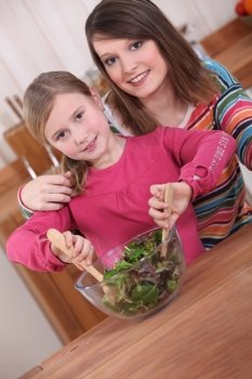 Young woman and daughter mixing salad