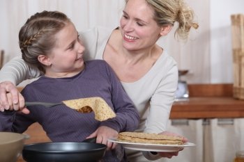 Mother and daughter having fun cooking pancakes