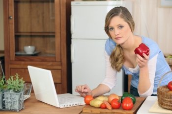 Woman cooking next to laptop