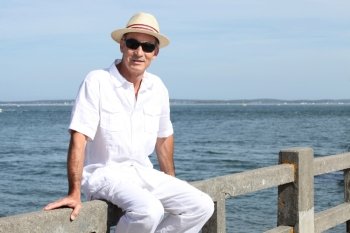 Senior in a straw panama hat sitting by the water