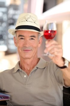 Elderly man toasting with glass of rose wine
