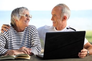 Senior couple in the garden with laptop and book