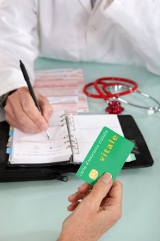 Patient handing social security card to doctor