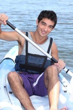 Dark-haired boy paddling in a canoe