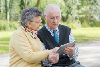 elderly couple with a tablet in the park