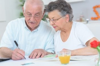 Elderly couple looking at magazine and taking notes