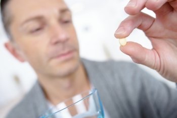 Man taking a tablet with a glass of water