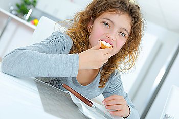 Little girl eating a snack in the kitchen