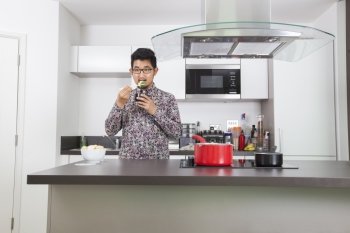 Young man eating broccoli at kitchen counter in home