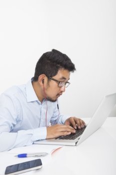 Concentrated businessman using laptop while listening music in office