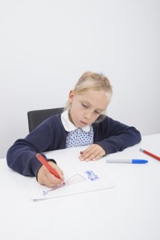 Little female student drawing on paper at table