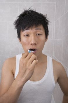 Sleepy mid adult man brushing teeth in bathroom
