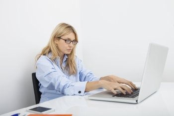 Young businesswoman using laptop at desk in office