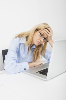 Exhausted businesswoman looking at laptop in office
