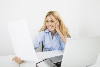 Happy businesswoman reading document in office