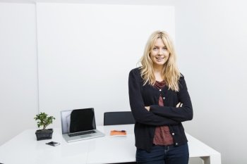 Portrait of happy businesswoman standing arms crossed in office