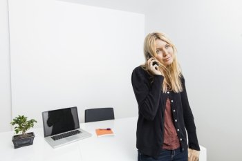 Businesswoman answering cell phone in office