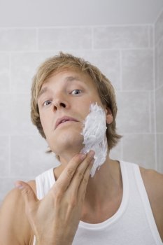 Portrait of man applying shaving cream in bathroom