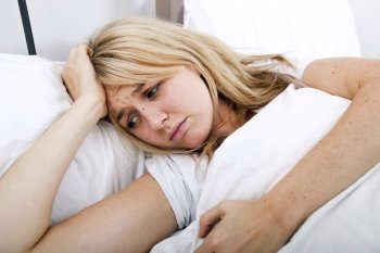 Young woman suffering from headache in bed