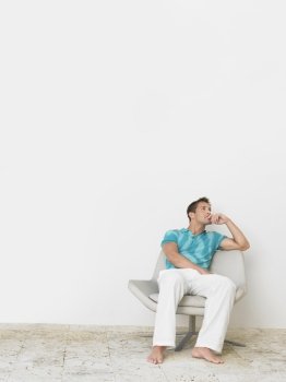 Full length of thoughtful young man sitting on chair
