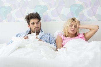 Frustrated sick couple lying in bed at home