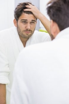 Reflection of man suffering from headache in mirror