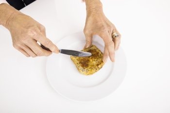 Businesswoman’s hands spreading butter on bread