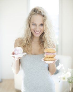 Portrait of happy woman with tea and donut in house
