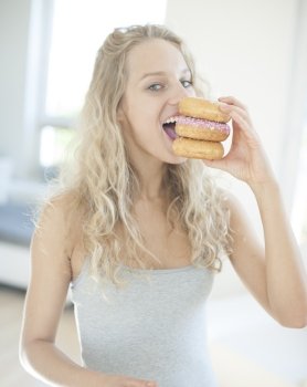 Portrait of happy woman eating donuts in house