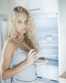 Portrait of sad woman having cherry tomato in kitchen