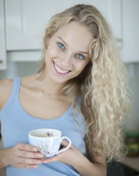 Portrait of happy woman holding tea cup in house