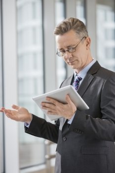 Businessman gesturing while using tablet PC in office